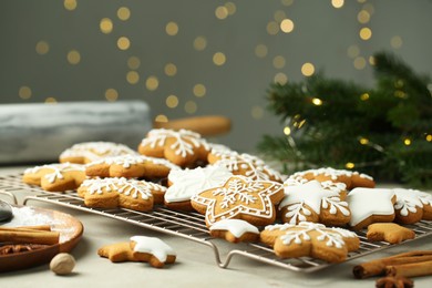 Photo of Tasty Christmas cookies with icing and spices on table against blurred lights