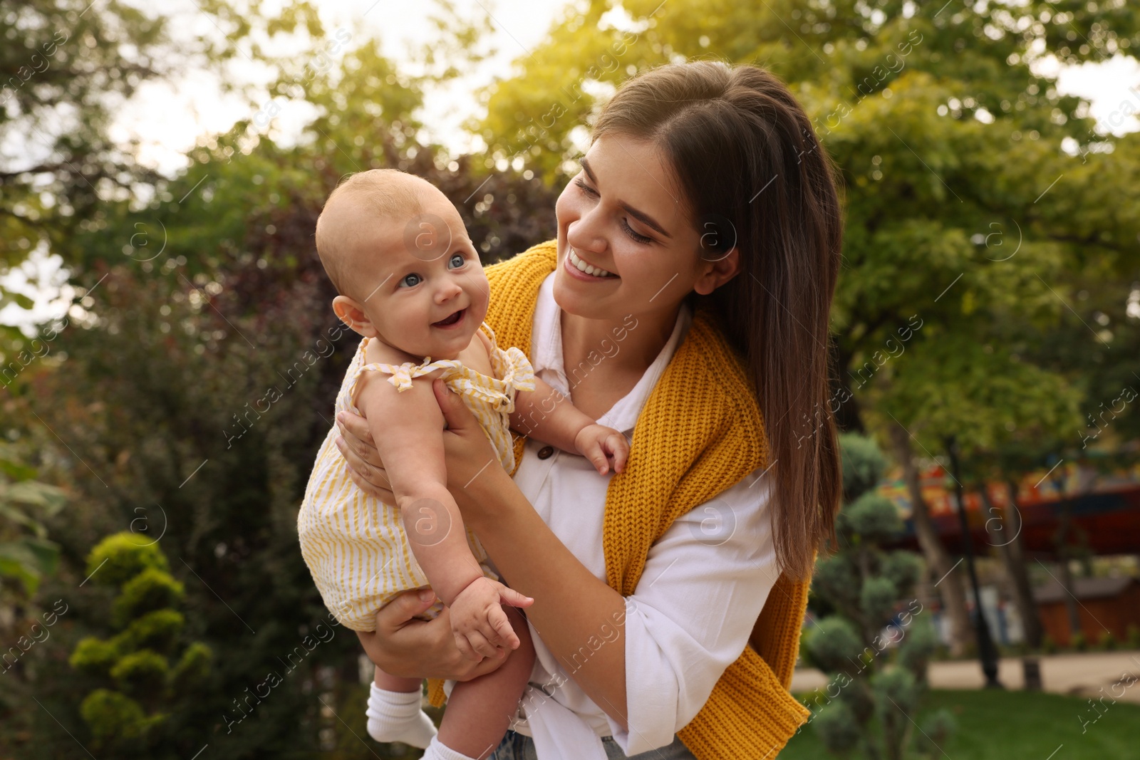 Photo of Happy mother with adorable baby walking in park on sunny day