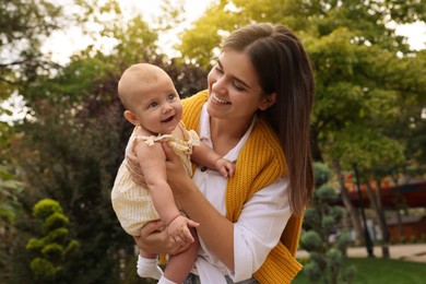 Happy mother with adorable baby walking in park on sunny day