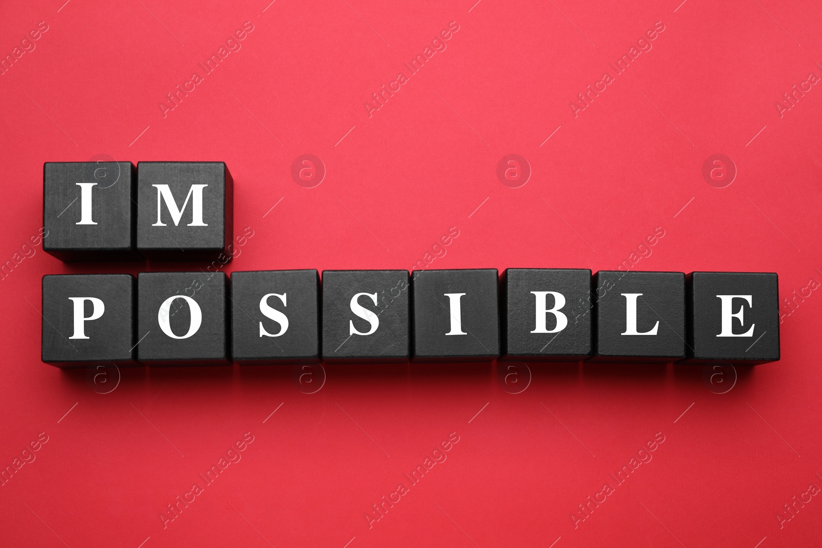 Photo of Motivation concept. Changing word from Impossible into Possible by removing black wooden cubes on red background, flat lay