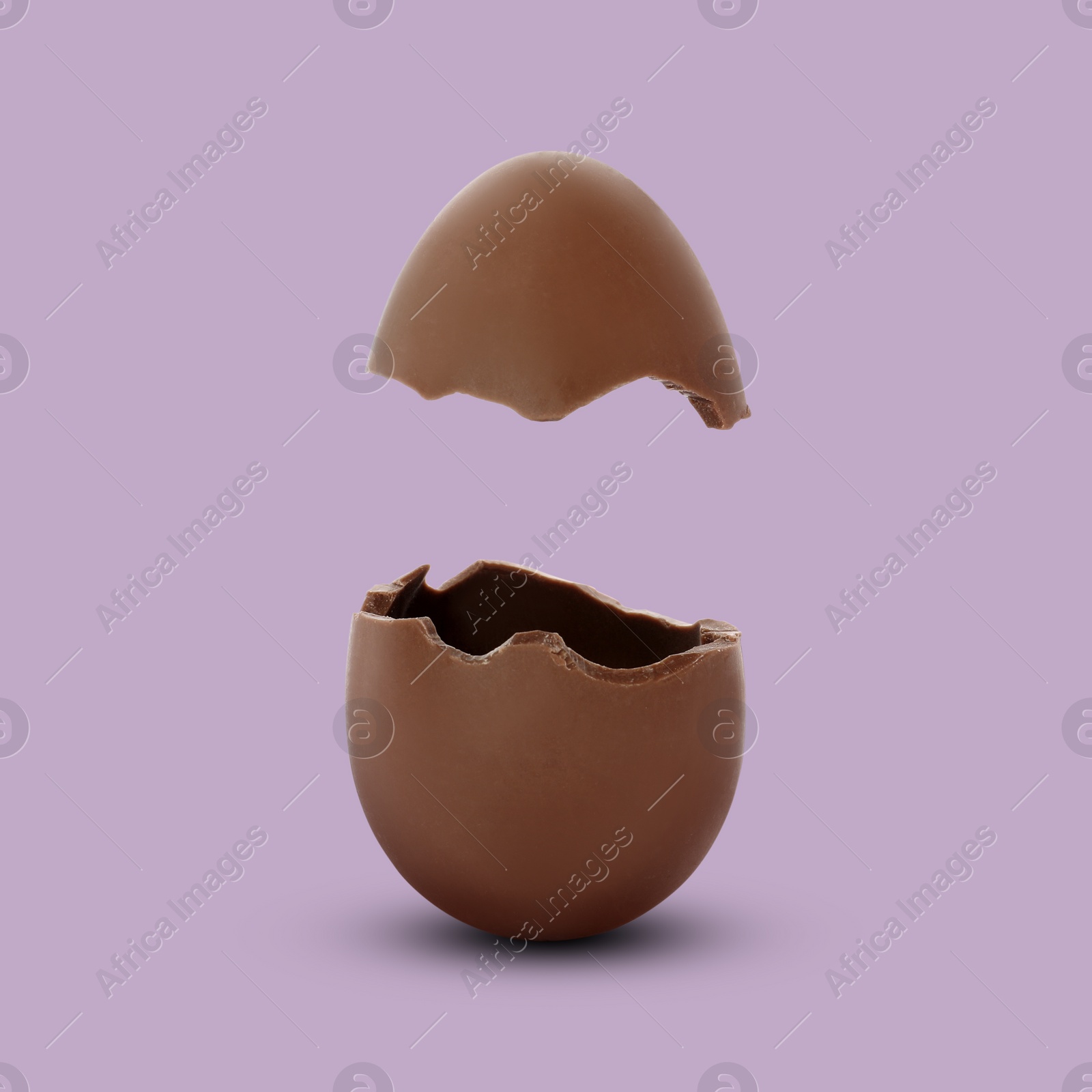 Image of Broken milk chocolate egg on mauve background