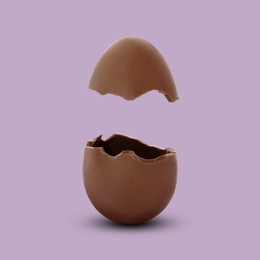 Broken milk chocolate egg on mauve background