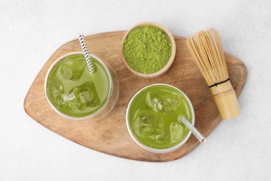 Photo of Delicious iced green matcha tea, powder and bamboo whisk on white table, top view