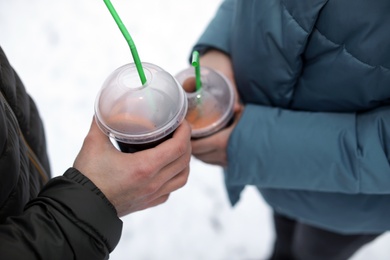 Young couple with cups of mulled wine outdoors, closeup