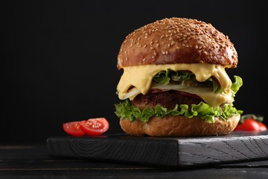 Photo of Vegetarian burger with delicious patty on black wooden table, closeup. Space for text