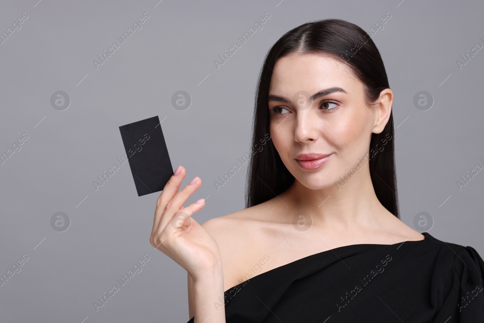 Photo of Woman holding blank business card on grey background. Space for text