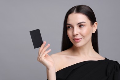 Woman holding blank business card on grey background. Space for text