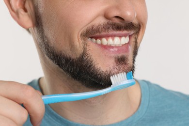 Man brushing his teeth with plastic toothbrush on white background, closeup