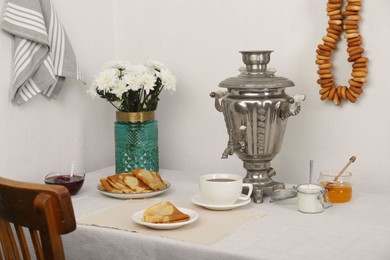 Photo of Vintage samovar, cuphot drink and snacks served on table indoors. Traditional Russian tea ceremony