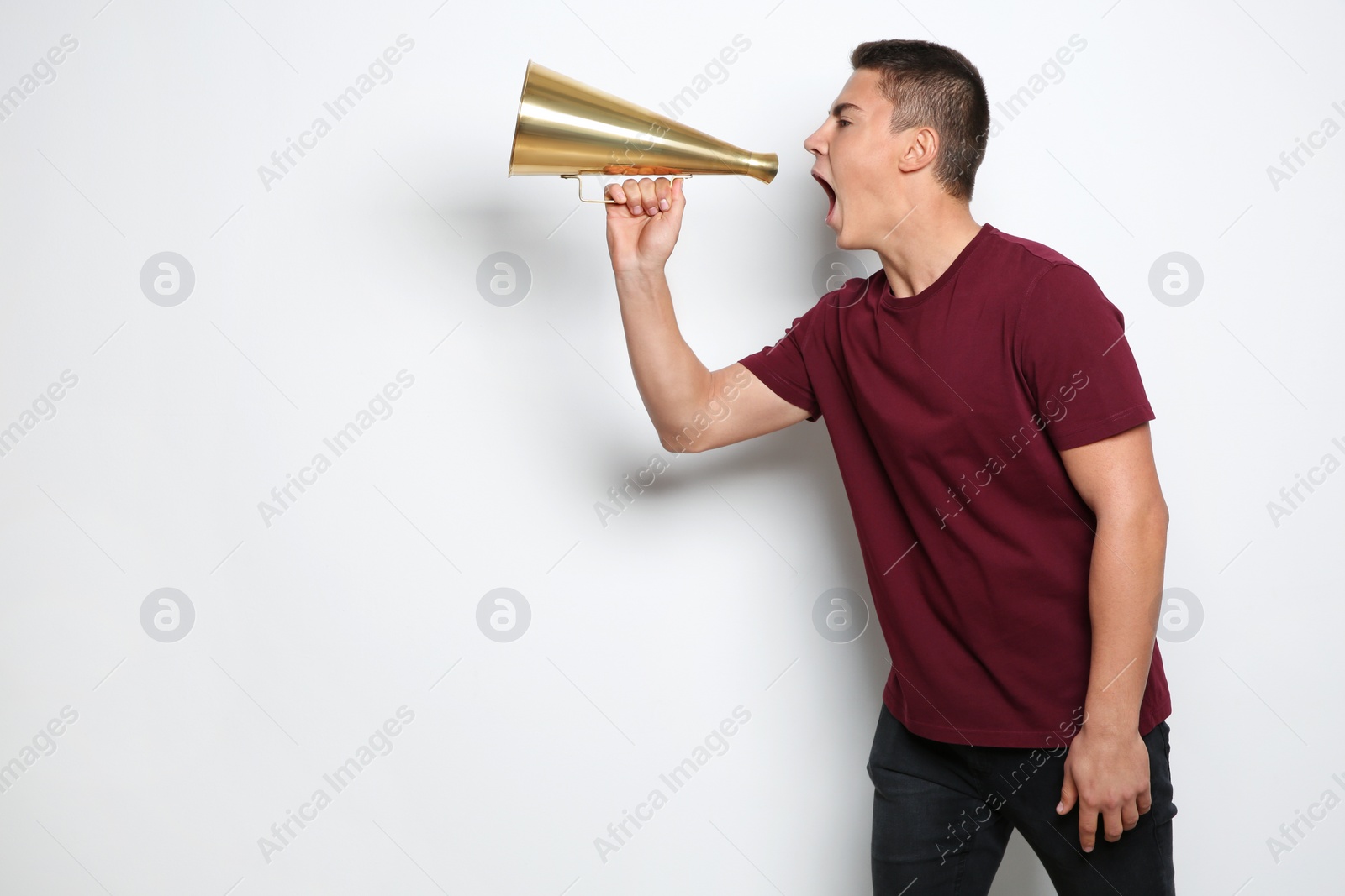 Photo of Emotional teenage boy with megaphone on white background. Space for text