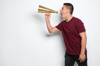 Photo of Emotional teenage boy with megaphone on white background. Space for text