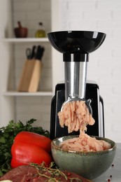 Photo of Electric meat grinder with chicken mince and products on table indoors