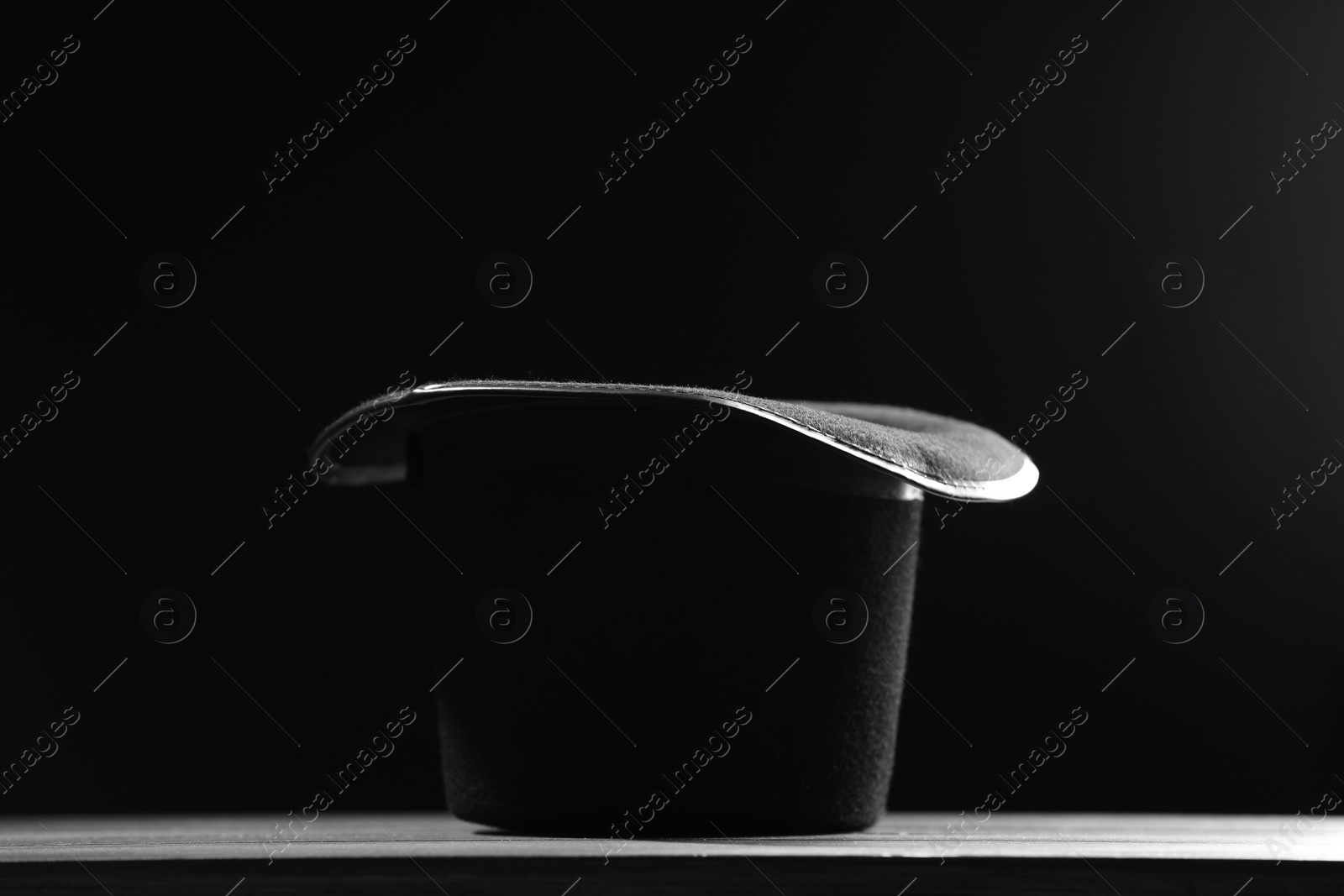 Photo of Magician's hat on white wooden table against black background