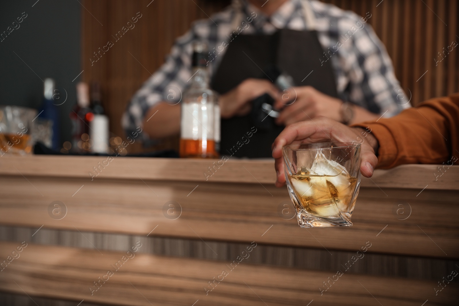 Photo of Young man with glass of whiskey in bar, closeup. Space for text