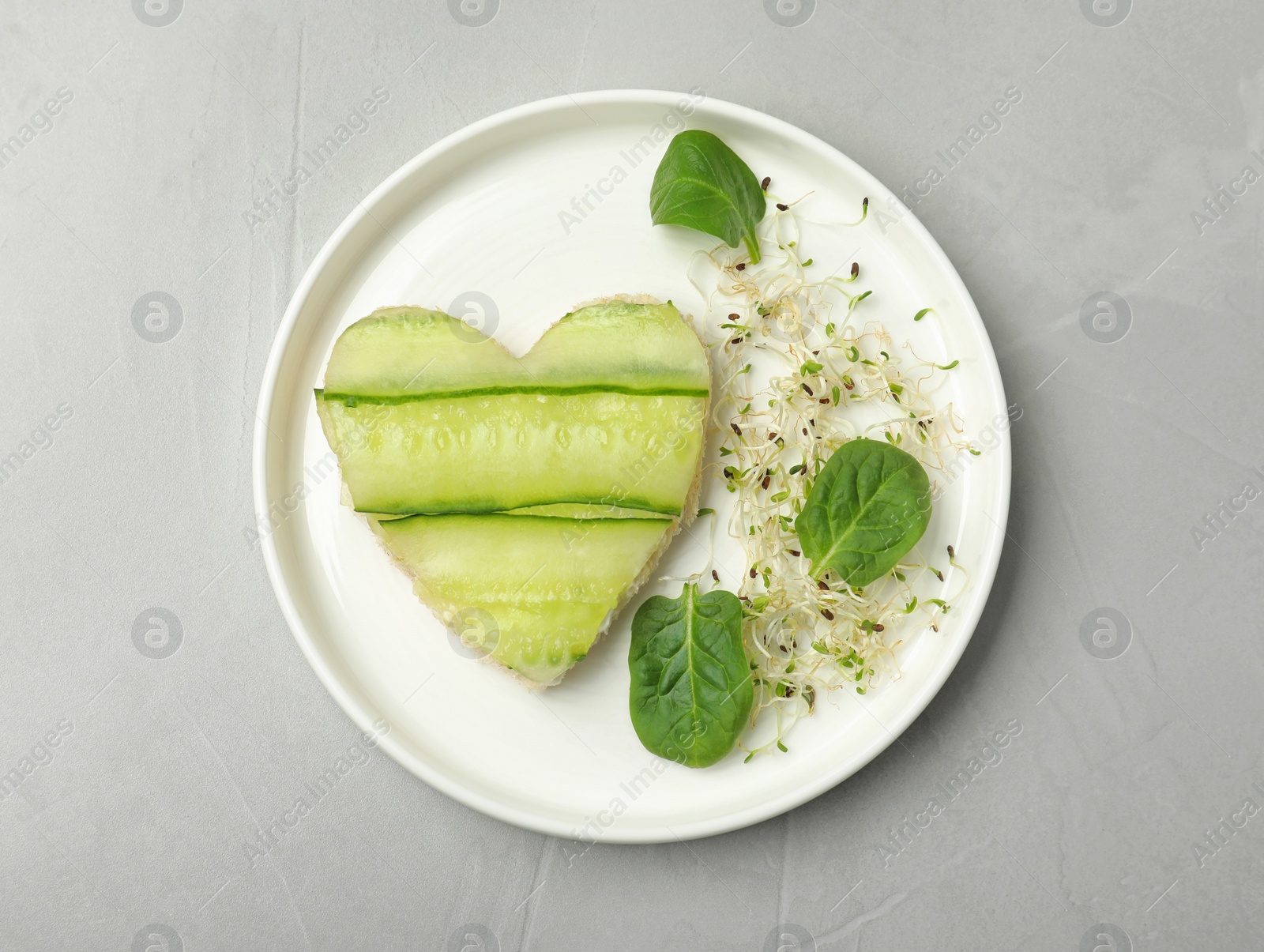 Photo of Plate with traditional English cucumber sandwich on grey background