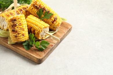 Photo of Tasty grilled corn cobs on light table. Space for text