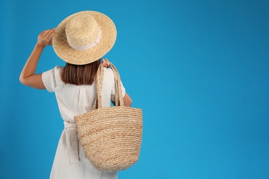 Young woman with stylish straw bag on light blue background. Space for text