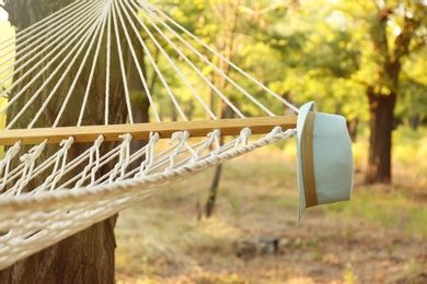 Comfortable net hammock and hat at green garden, closeup