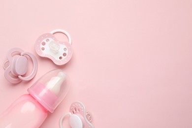 Photo of Flat lay composition with pacifiers and other baby stuff on pink background. Space for text