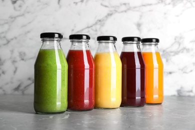 Photo of Bottles with delicious colorful juices on marble table