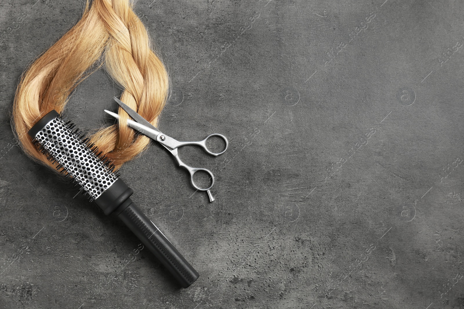 Photo of Professional hairdresser scissors, brush and strand of blonde hair on grey background, top view