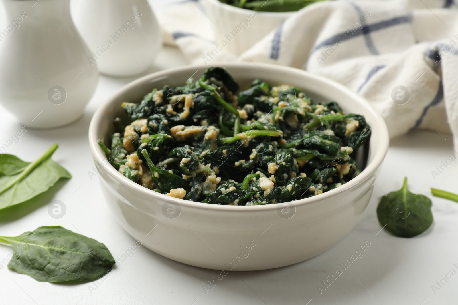 Photo of Tasty spinach dip with eggs in bowl on white table, closeup