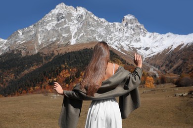 Young woman walking in beautiful mountains on sunny day, back view