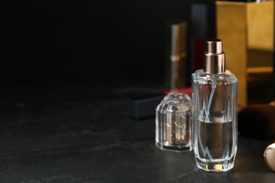 Photo of Bottle of perfume on dark table. Space for text