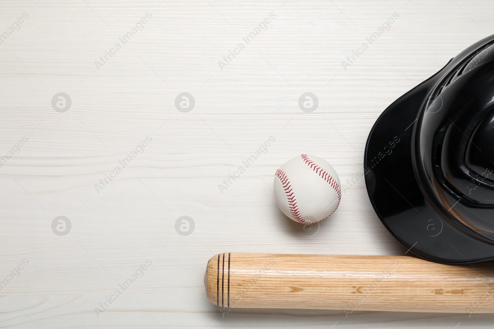 Photo of Sports equipment. Helmet, ball and baseball bat on white wooden table, flat lay. Space for text