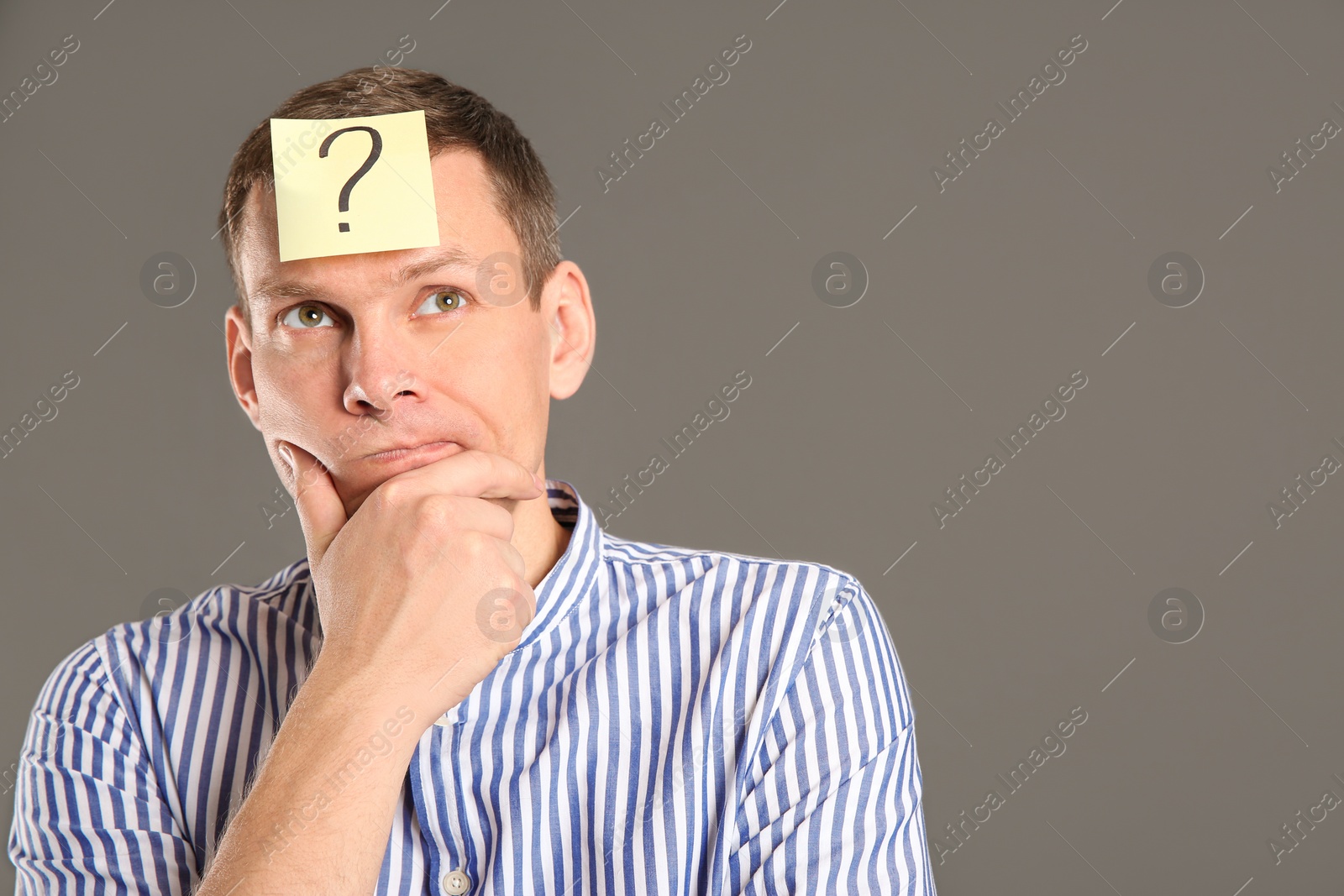 Photo of Emotional man with question mark on grey background, space for text