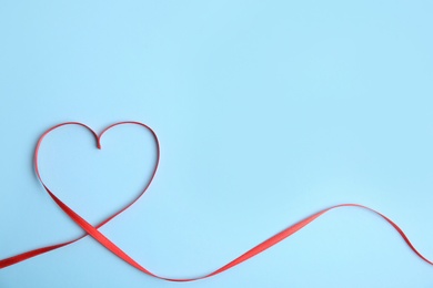 Heart made of red ribbon on light blue background, top view with space for text. Valentine's day celebration