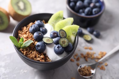 Photo of Tasty granola in bowl served on gray table, closeup