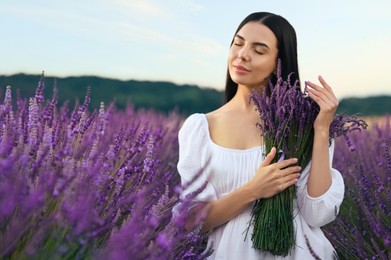 Beautiful young woman with bouquet in lavender field