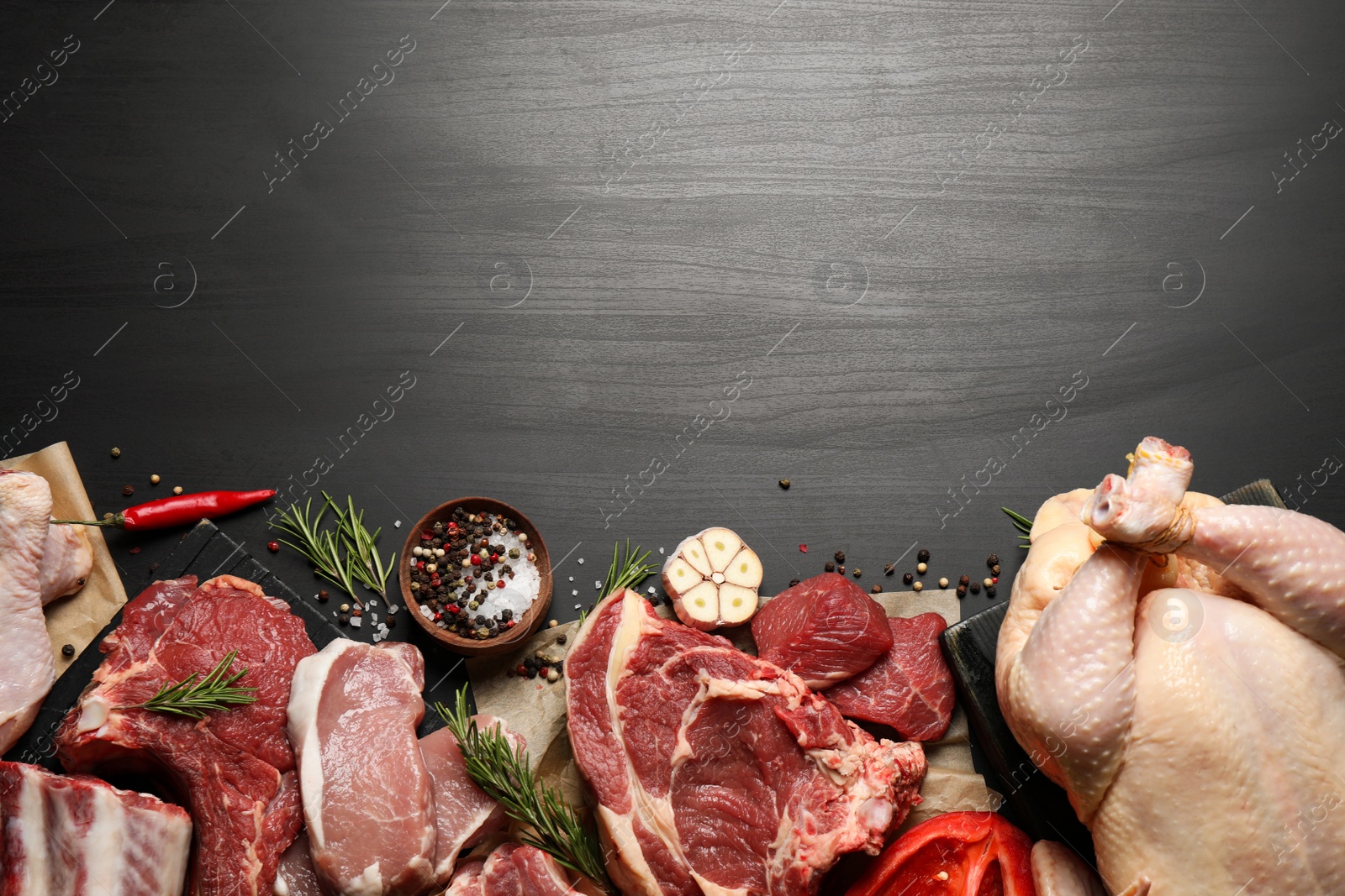 Photo of Flat lay composition with fresh meat on dark table. Space for text