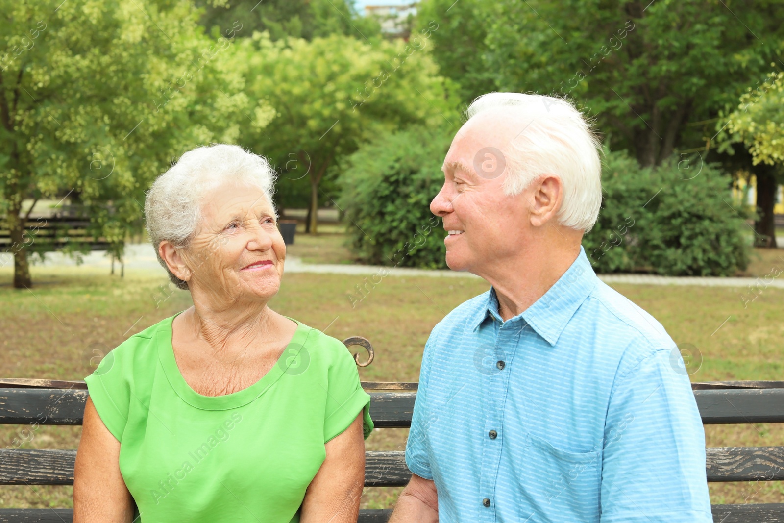 Photo of Elderly couple resting on bench in park