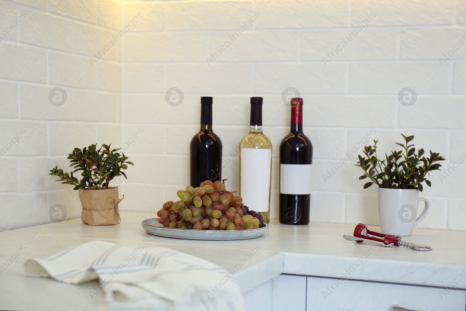 Photo of Red wine and grapes on white countertop in modern kitchen