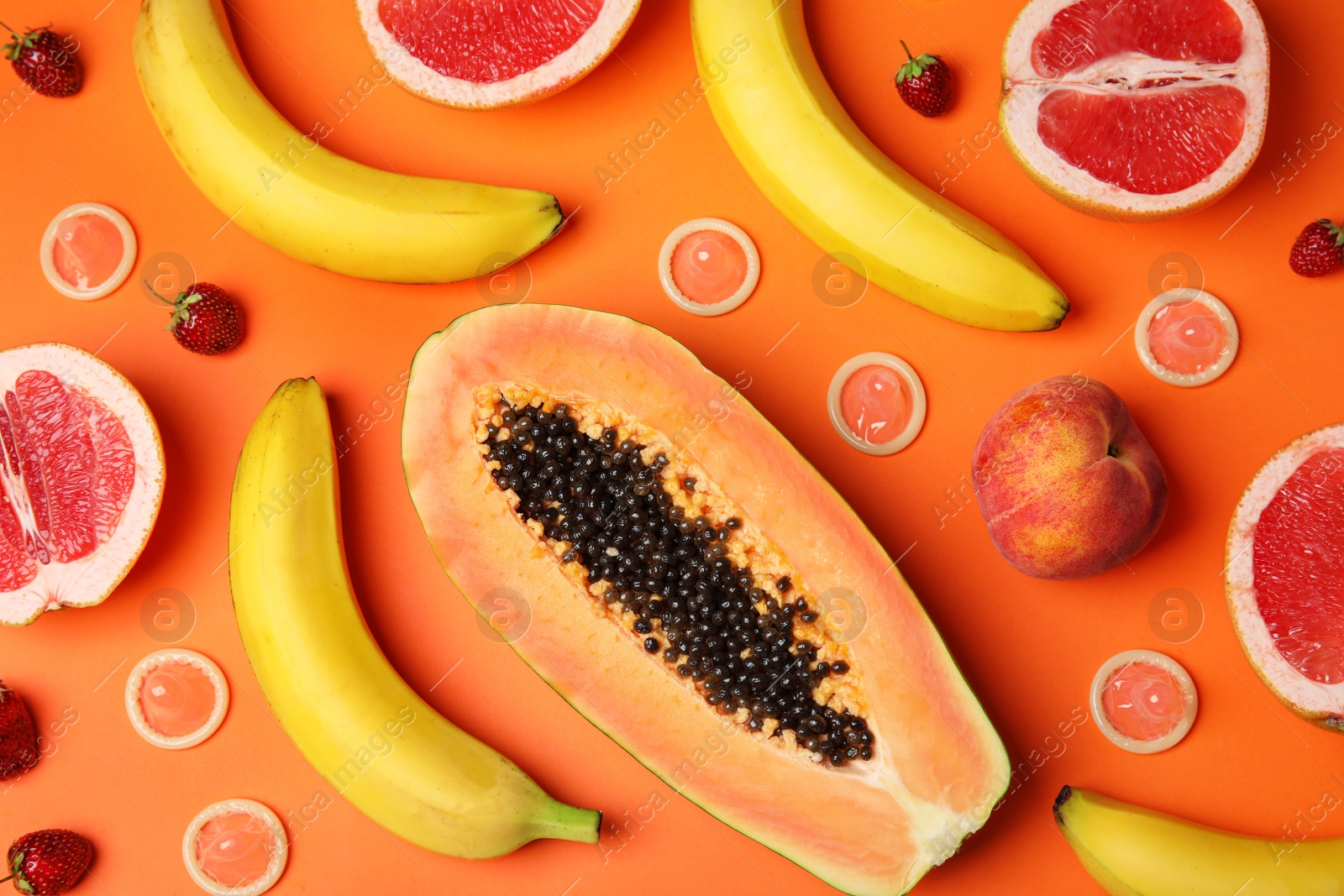 Photo of Flat lay composition with condoms and exotic fruits on orange background. Erotic concept