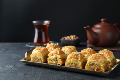 Photo of Delicious fresh baklava with chopped nuts on dark textured table, closeup and space for text. Eastern sweets