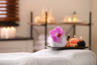 Photo of Composition with towel, candles and oils on massage table in spa salon. Space for text