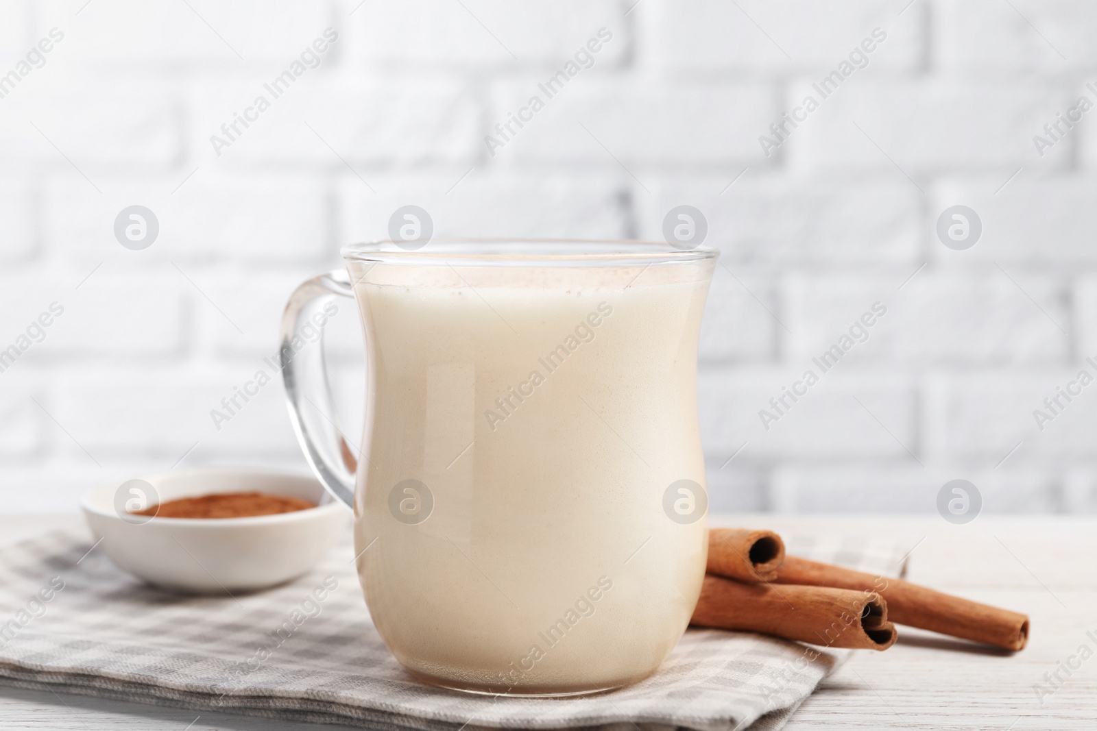 Photo of Delicious eggnog with cinnamon on wooden table, closeup