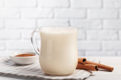 Delicious eggnog with cinnamon on wooden table, closeup