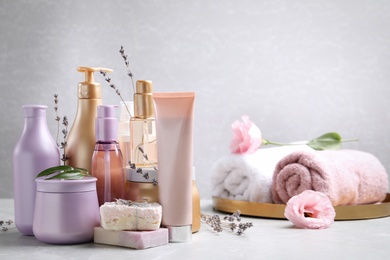 Photo of Set of hair cosmetic products and flowers on grey table