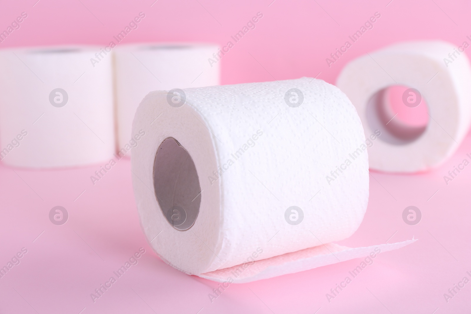 Photo of Soft toilet paper rolls on pink background, closeup