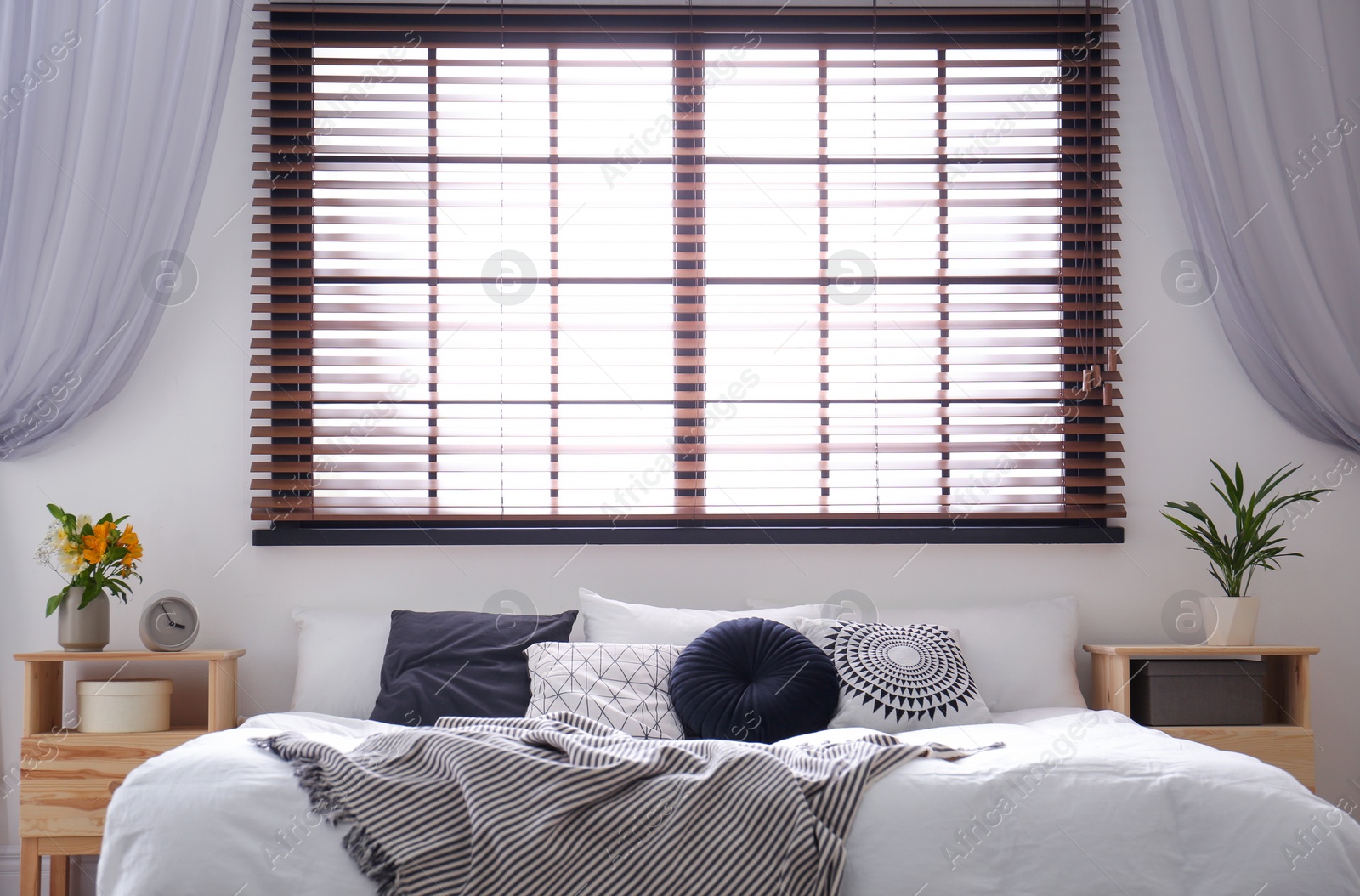 Photo of Modern room interior with comfortable double bed and window blinds