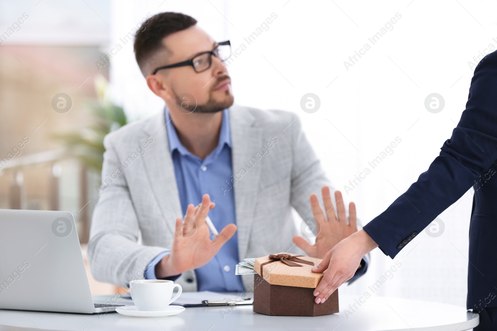 Photo of Businessman refusing to take bribe at table indoors