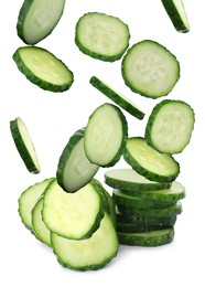 Slices of fresh green cucumbers falling on white background