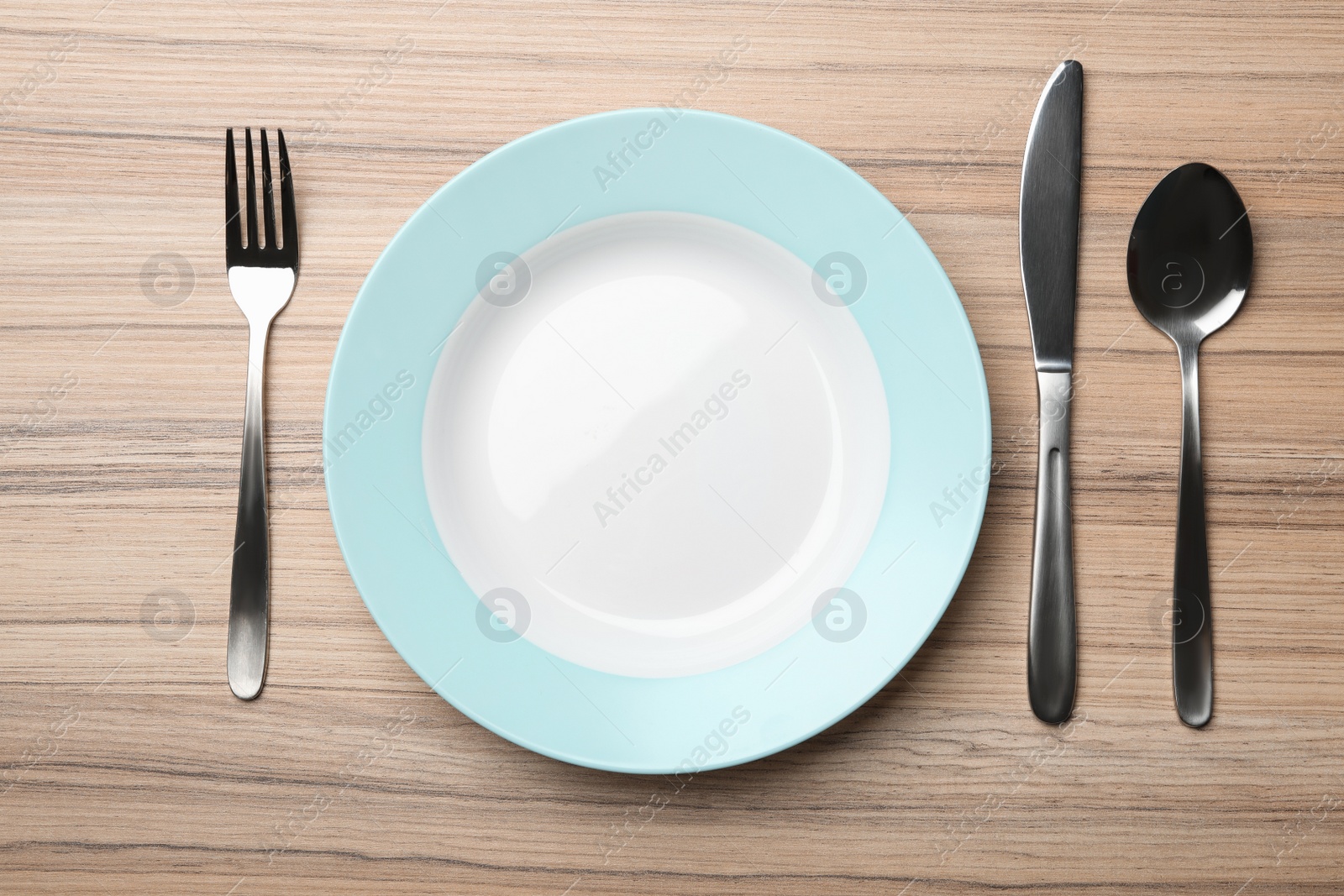 Photo of Stylish ceramic plate and cutlery on wooden background, flat lay