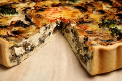 Photo of Delicious quiche with mushrooms on wooden board, closeup