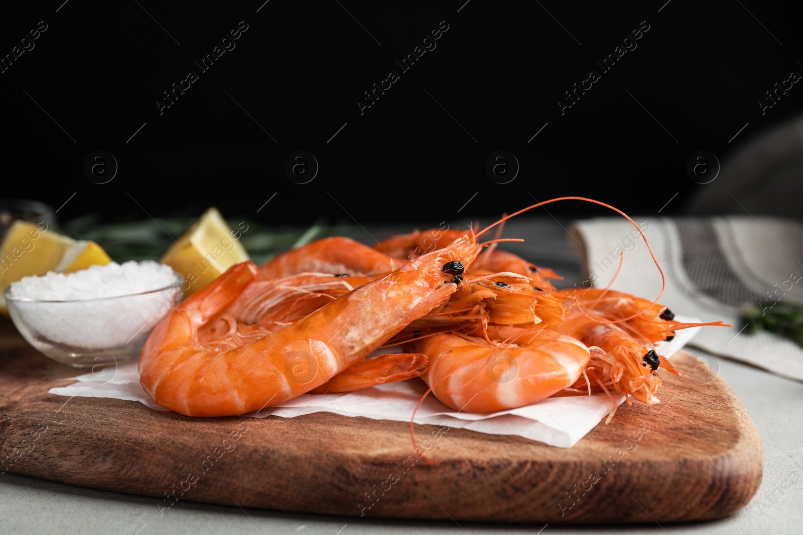 Photo of Delicious cooked shrimps and salt on wooden board