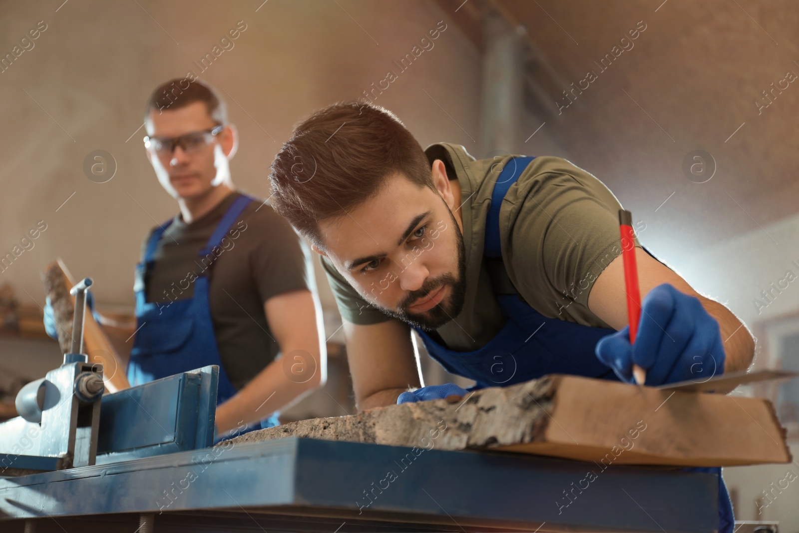 Photo of Professional carpenter making mark on wooden board in workshop